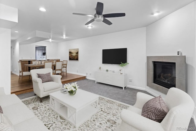 living room featuring hardwood / wood-style flooring, a tile fireplace, and ceiling fan