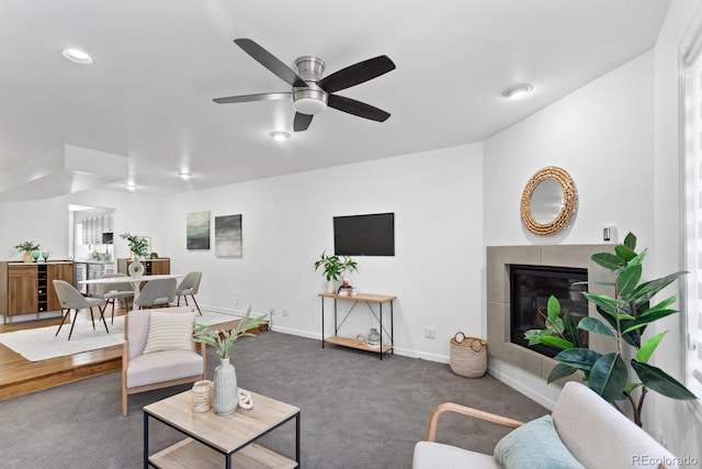 living room with a tiled fireplace, recessed lighting, carpet floors, baseboards, and ceiling fan