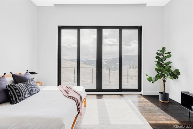 bedroom with baseboards, a mountain view, wood finished floors, and access to exterior