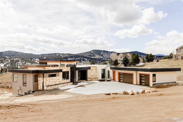 view of front of home featuring stone siding, driveway, a mountain view, and an attached garage