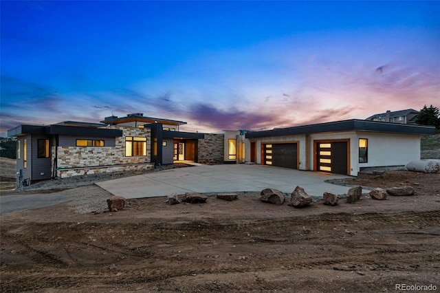 contemporary home featuring stone siding, concrete driveway, and an attached garage
