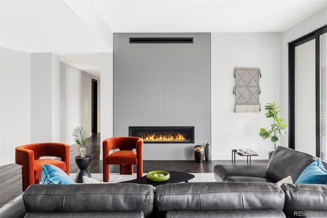 living area featuring visible vents, a glass covered fireplace, and wood finished floors