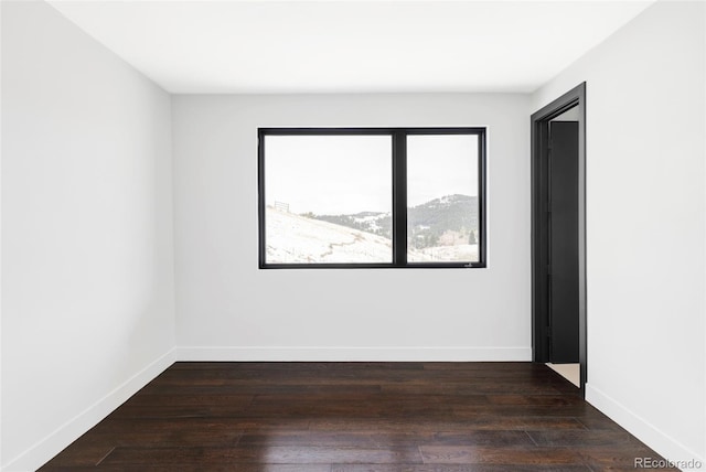 spare room with baseboards and wood finished floors