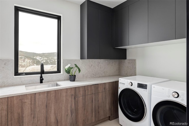 laundry area with washing machine and clothes dryer, cabinet space, and a sink