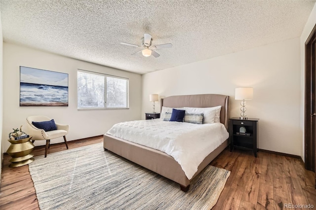 bedroom featuring a ceiling fan, baseboards, a textured ceiling, and wood finished floors