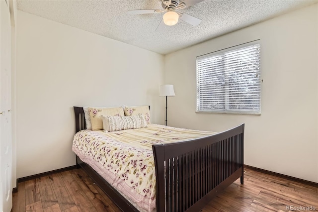 bedroom with baseboards, a textured ceiling, and wood finished floors