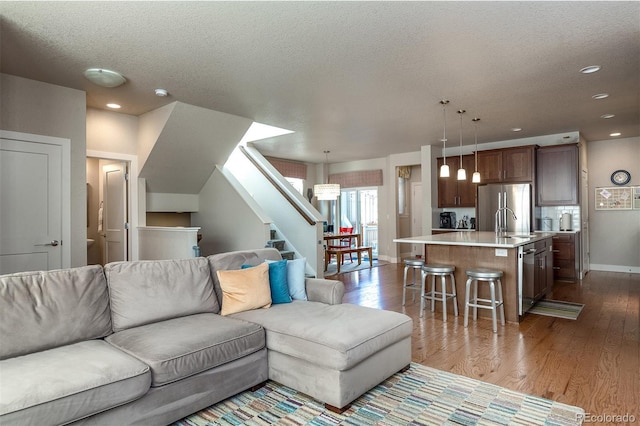 living room featuring hardwood / wood-style floors, sink, and a textured ceiling