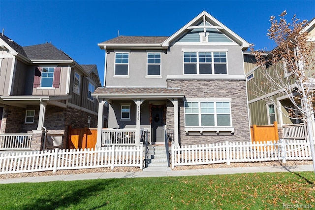 view of front facade with a porch, stone siding, a fenced front yard, and stucco siding