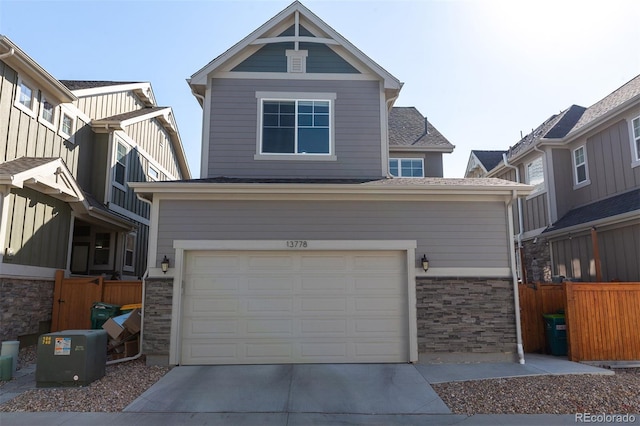 view of front facade with an attached garage, stone siding, and concrete driveway