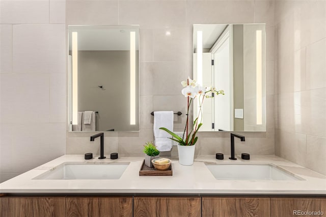 full bath featuring double vanity, tile walls, and a sink