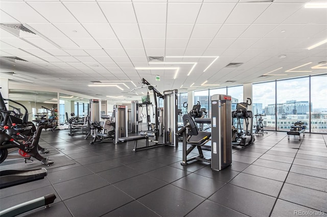 gym with a paneled ceiling, a wall of windows, and visible vents