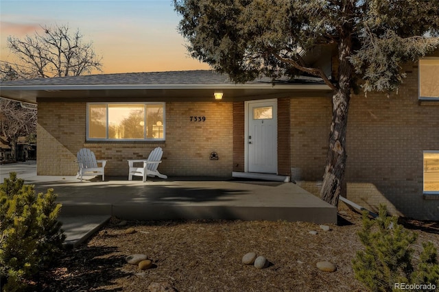 view of front of home featuring a patio area and brick siding