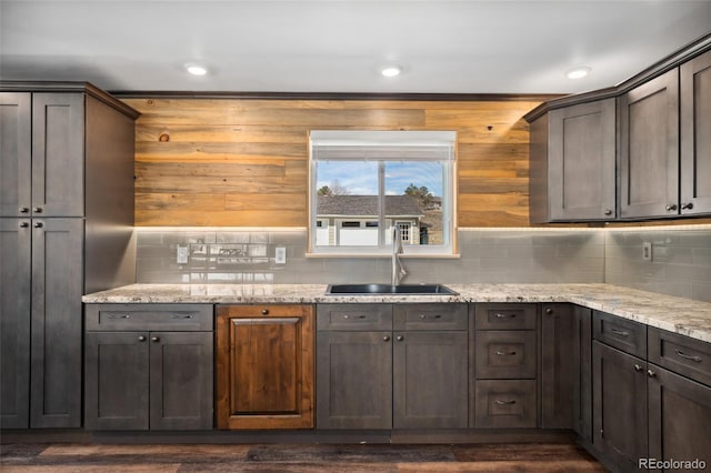 kitchen with light stone counters, backsplash, a sink, and recessed lighting