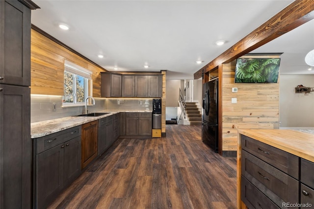 kitchen with dark wood-style flooring, a sink, dark brown cabinets, decorative backsplash, and black refrigerator with ice dispenser