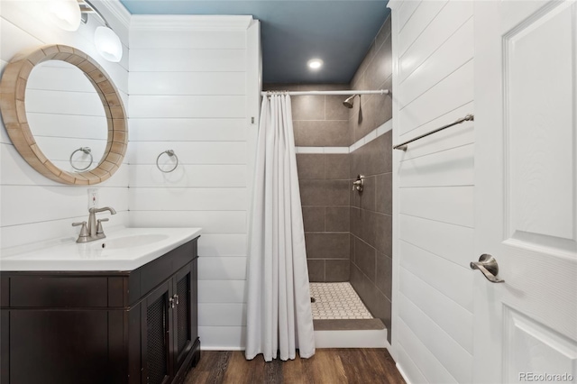 bathroom featuring a tile shower, wood finished floors, and vanity