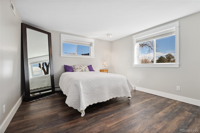 bedroom with visible vents, baseboards, and wood finished floors