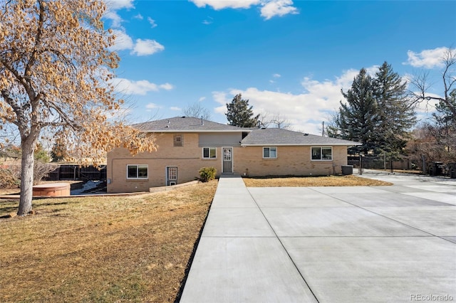 back of house featuring a patio area, brick siding, a yard, and fence