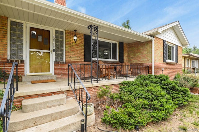 4040 Cody St, Wheat Ridge, CO 80033 - view of exterior entry with brick siding, a porch, and a chimney
