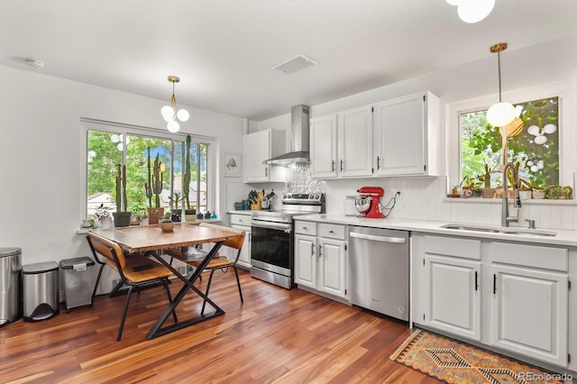 4040 Cody St, Wheat Ridge, CO 80033 - kitchen with appliances with stainless steel finishes, wall chimney exhaust hood, light countertops, and healthy amount of natural light