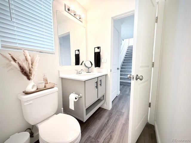 bathroom featuring toilet, baseboards, wood finished floors, and vanity
