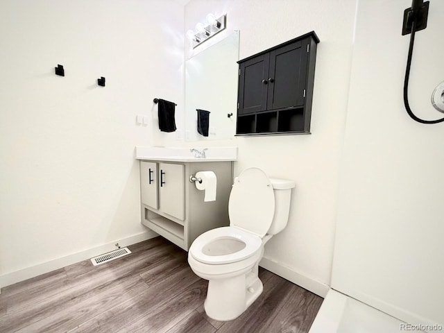 bathroom featuring vanity, baseboards, wood finished floors, and visible vents