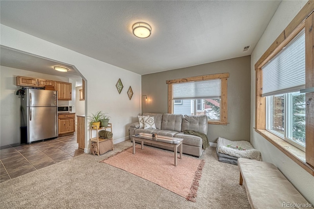 living room with dark carpet, a wealth of natural light, and a textured ceiling