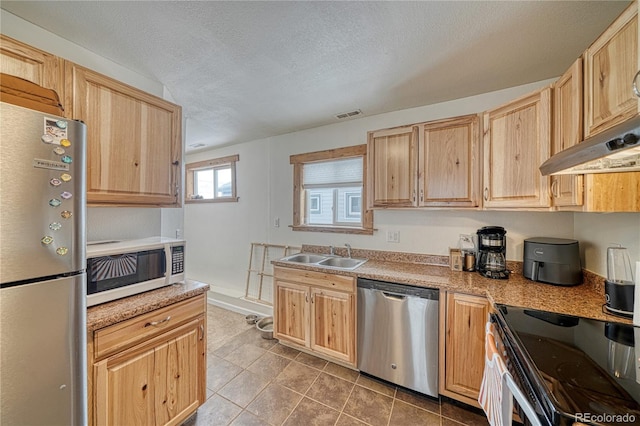 kitchen with appliances with stainless steel finishes, tile patterned flooring, sink, and light brown cabinets