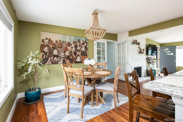 dining room with plenty of natural light, beam ceiling, a fireplace, and wood-type flooring