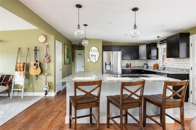 kitchen with stainless steel fridge with ice dispenser, pendant lighting, and light stone counters