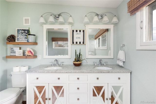 bathroom featuring toilet, vanity, and a healthy amount of sunlight