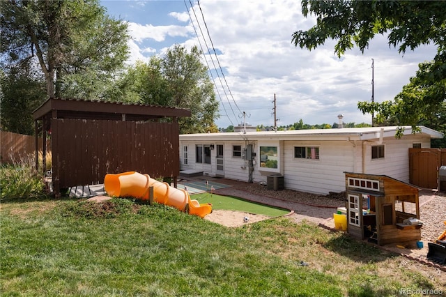 back of house with central air condition unit and a yard