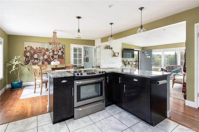 kitchen with light stone countertops, stainless steel electric stove, kitchen peninsula, and decorative light fixtures