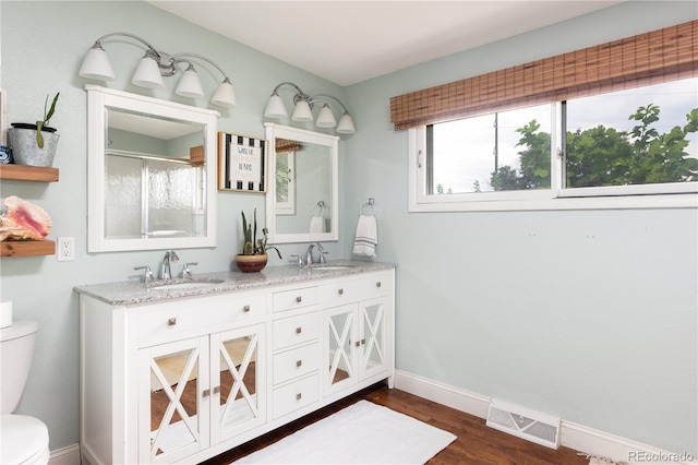 bathroom with toilet, vanity, a shower with shower door, and hardwood / wood-style floors