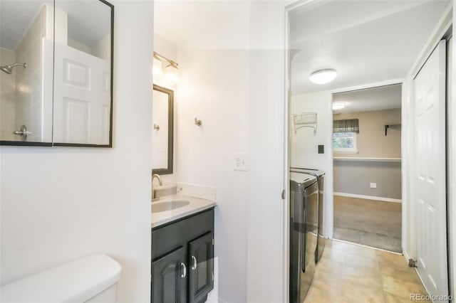 bathroom with toilet, vanity, and washing machine and clothes dryer