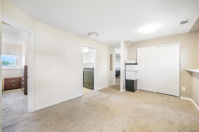 unfurnished living room with carpet floors, washer / clothes dryer, and baseboards
