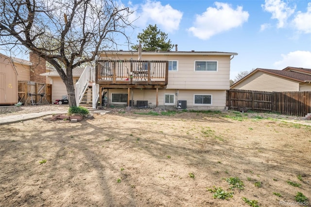 rear view of property with a deck, a fenced backyard, stairway, and central AC