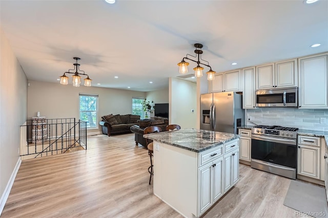15691 E Atlantic Cir, Aurora, CO 80013 - kitchen featuring stainless steel appliances, light wood-style floors, dark stone countertops, a kitchen island, and hanging light fixtures