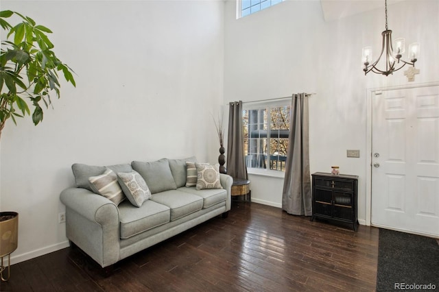 living room with dark wood-type flooring, a high ceiling, and a chandelier