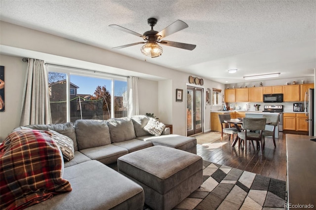 living room featuring ceiling fan, dark wood-type flooring, and a textured ceiling