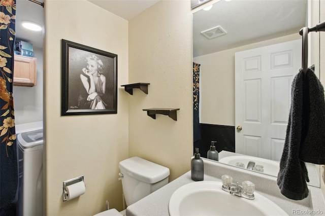 bathroom featuring washer / clothes dryer, sink, and toilet