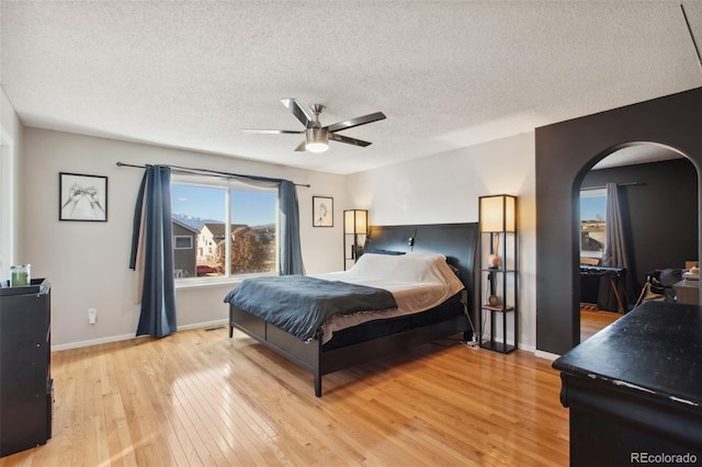 bedroom with a textured ceiling, light hardwood / wood-style flooring, and ceiling fan