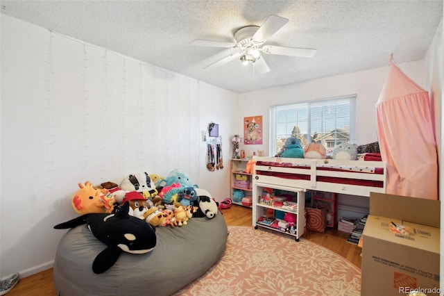 bedroom with ceiling fan, light hardwood / wood-style floors, and a textured ceiling