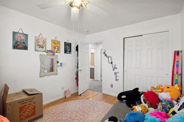 bedroom featuring ceiling fan, a closet, a textured ceiling, and light hardwood / wood-style flooring