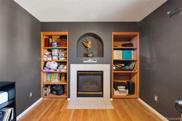 living room with a fireplace, a textured ceiling, and light hardwood / wood-style floors