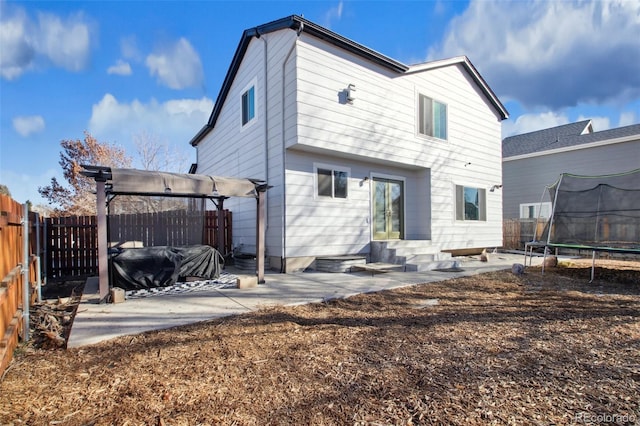 back of house with a trampoline and a patio area