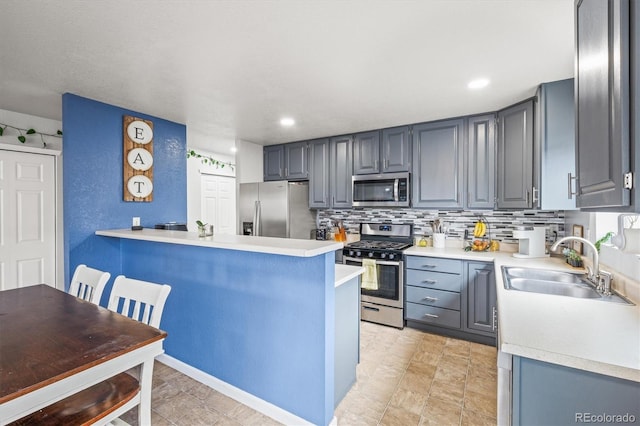 kitchen with gray cabinetry, sink, tasteful backsplash, kitchen peninsula, and stainless steel appliances