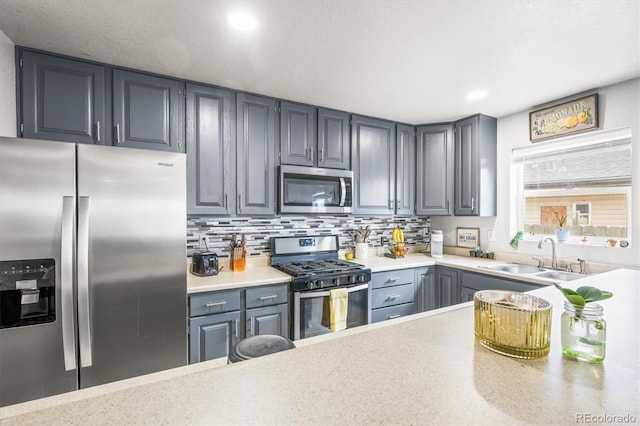 kitchen featuring backsplash, gray cabinetry, sink, and stainless steel appliances