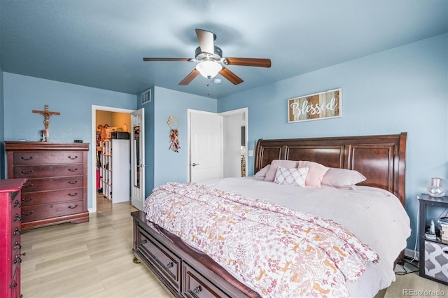 bedroom with ceiling fan, light hardwood / wood-style floors, a walk in closet, and a closet