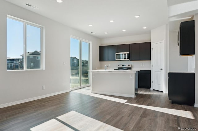 kitchen featuring sink, appliances with stainless steel finishes, dark hardwood / wood-style flooring, and an island with sink