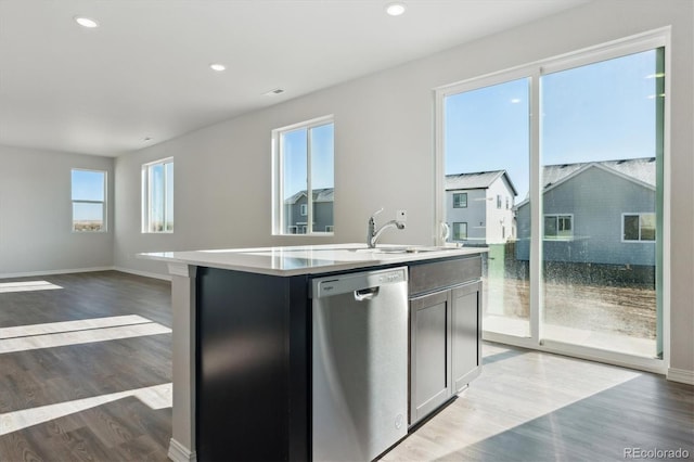 kitchen with sink, dark hardwood / wood-style floors, stainless steel dishwasher, and an island with sink